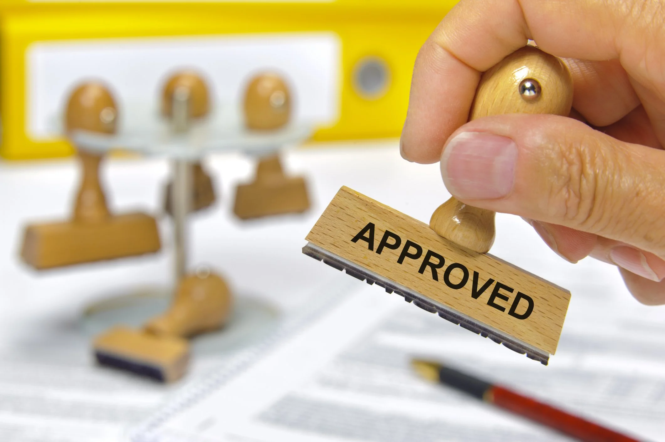 Hand holding an approved stamp over paperwork, representing professional reusable quote templates.