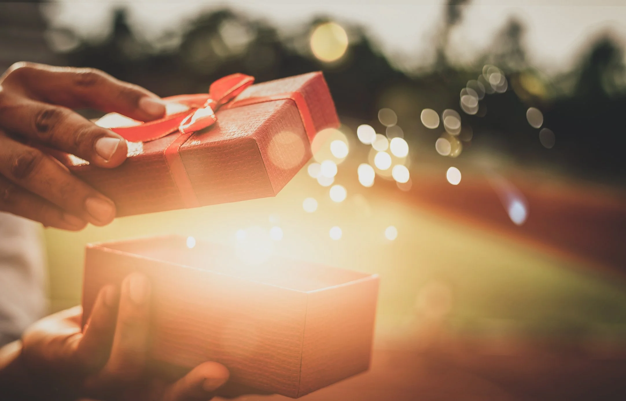 Hands opening a glowing gift box, representing the hidden possibilities of custom fields in VSCO Workspace.