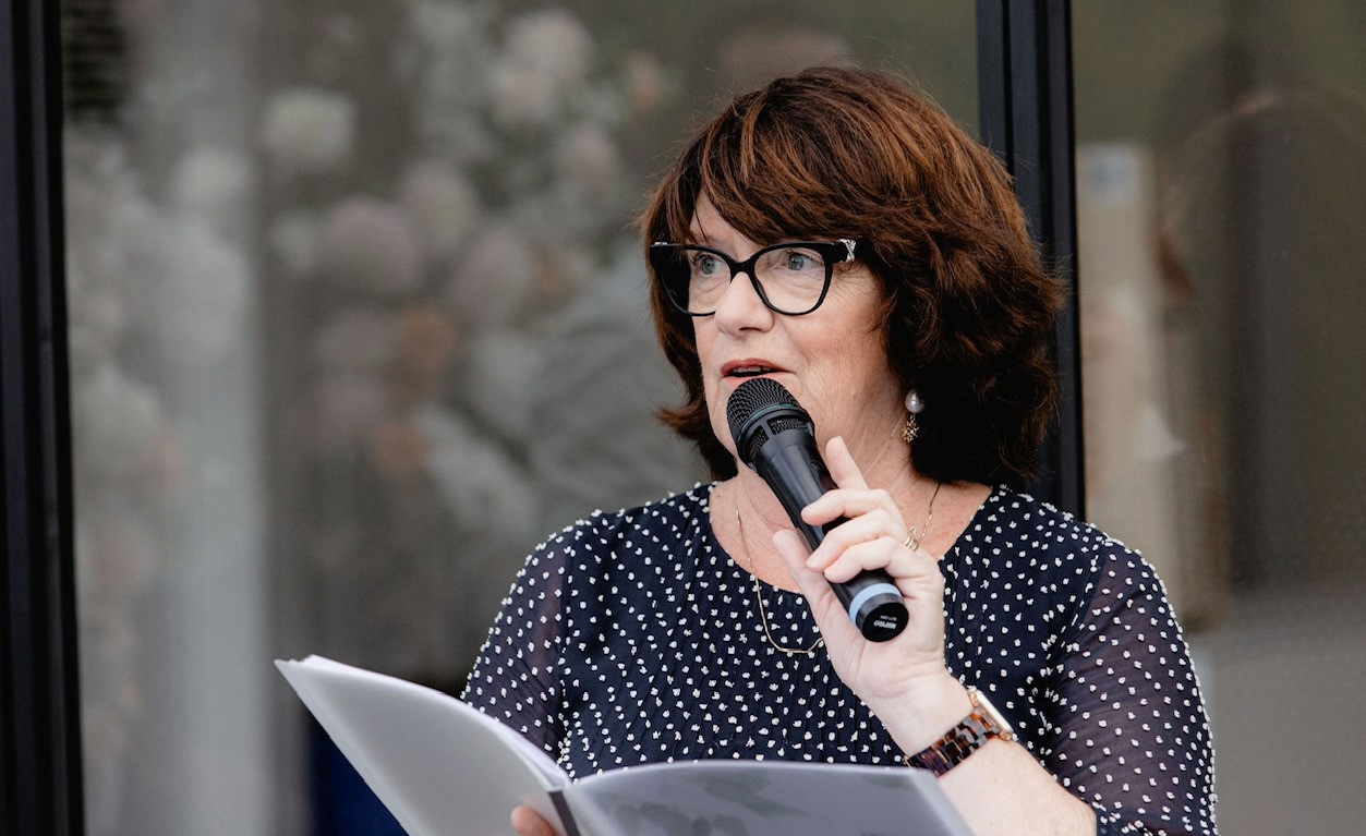 Celebrant speaking into a microphone while holding ceremony notes.