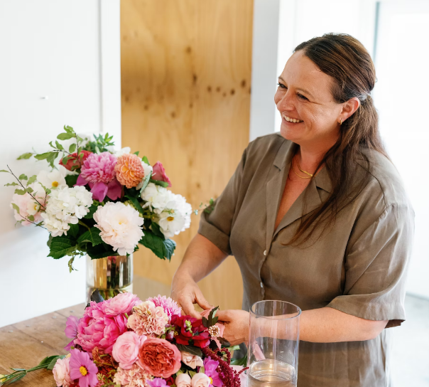Florist smiling while arranging colourful flowers in her studio.