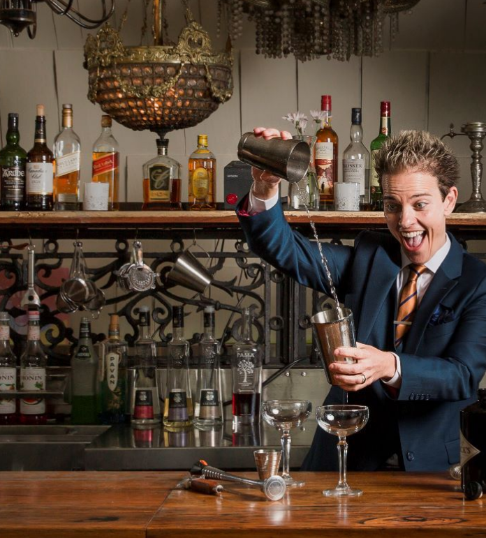 Celebrant enthusiastically preparing drinks behind a bar.