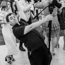 Videographer adjusting camera equipment while filming an event.