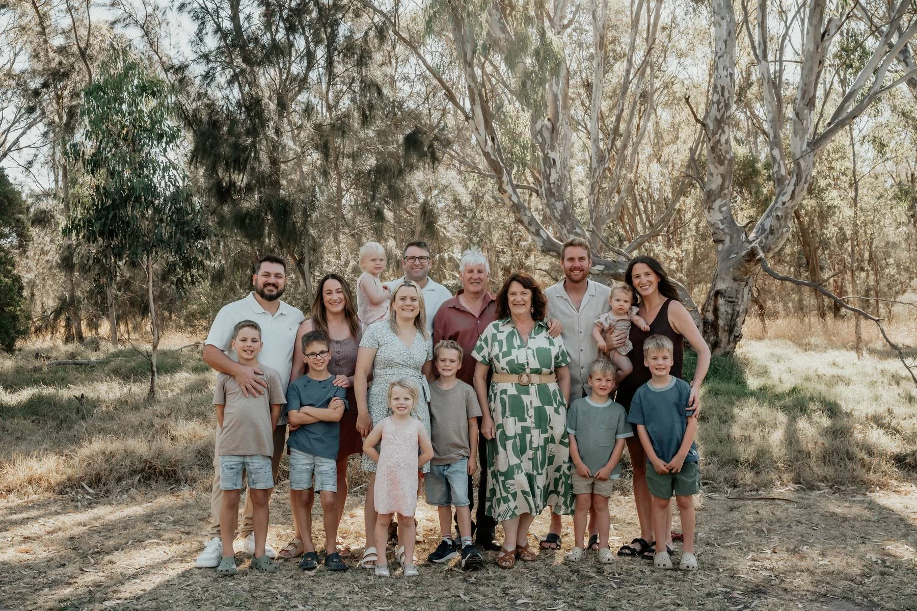 Large family group gathered outdoors among Australian gum trees.