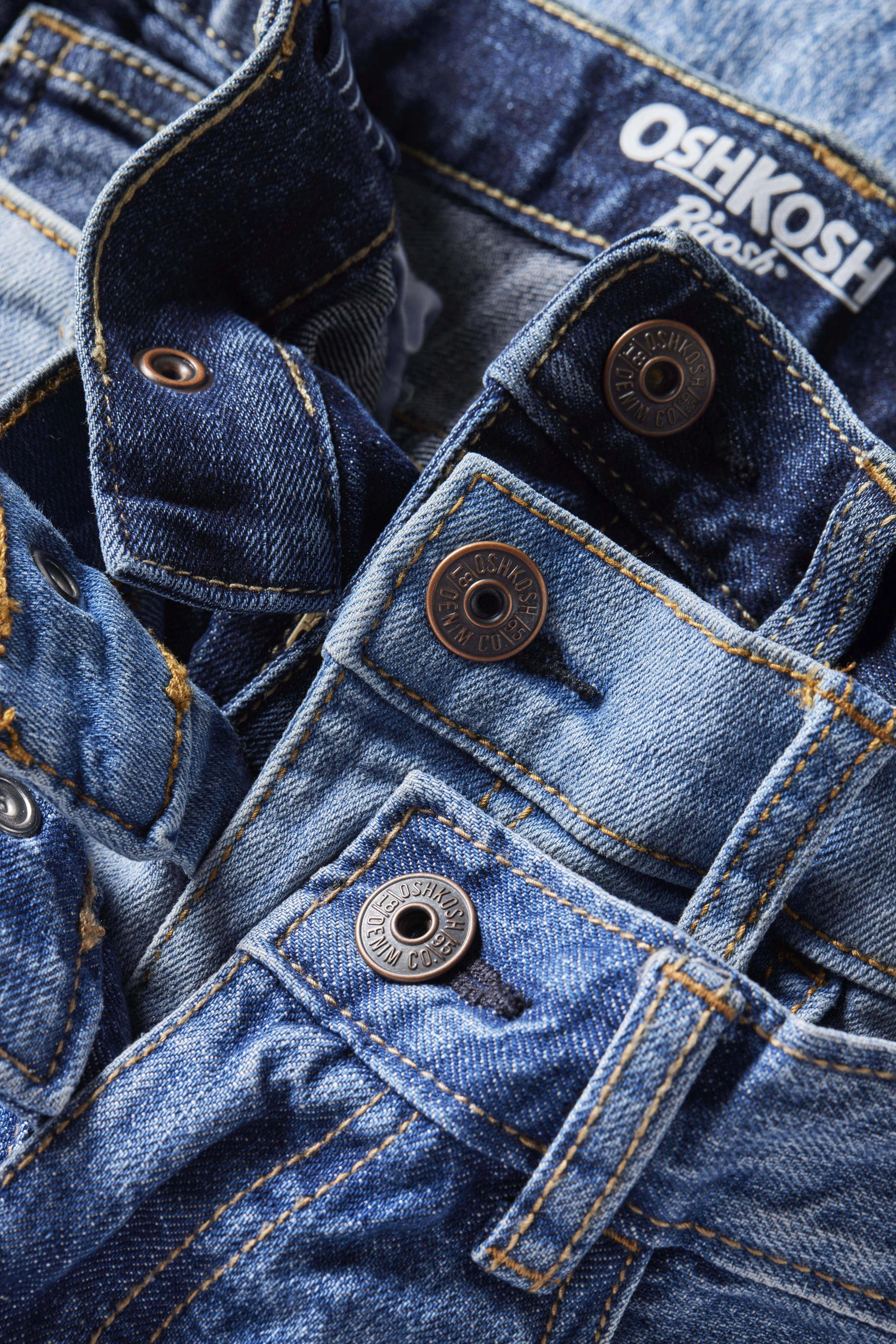 Close-up of several blue denim jeans folded with visible buttons and stitching.