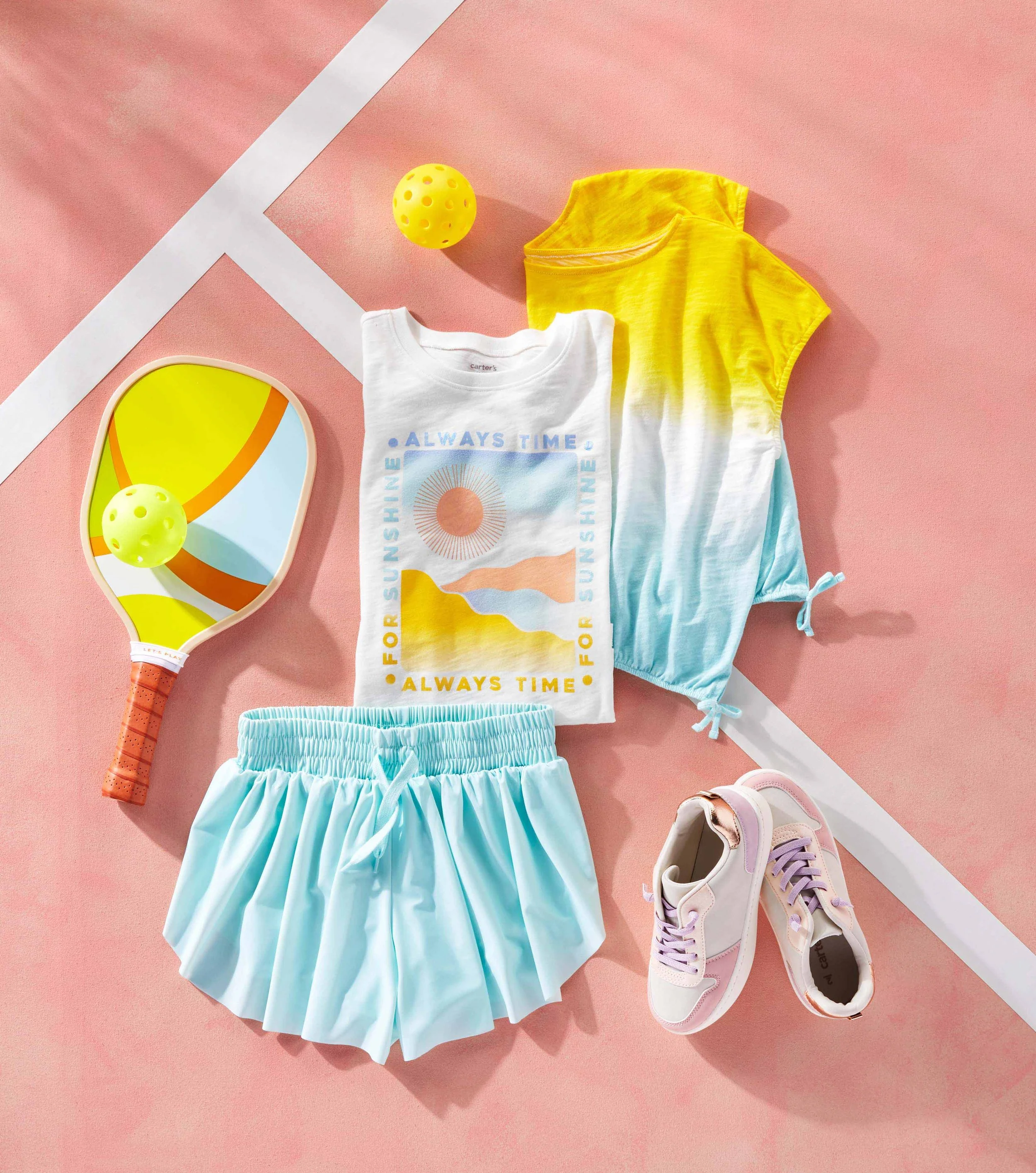 A pink background with a white sports line, featuring children's clothing and accessories including a white t-shirt, a yellow tie-dye shirt, light blue shorts, purple and white sneakers, a hand mirror, a yellow ball, and a pair of pastel pink sneaker