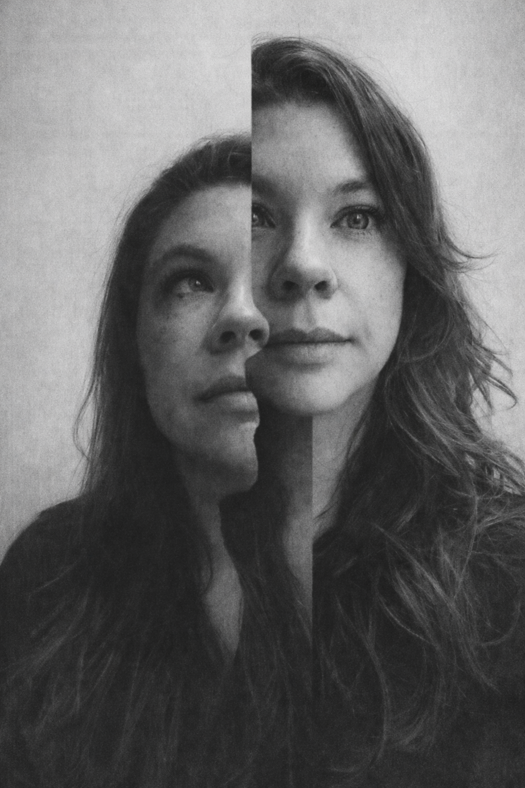 Black and white photo of a woman with long wavy hair, with a mirror image of her face positioned next to her, creating an artistic symmetrical effect.