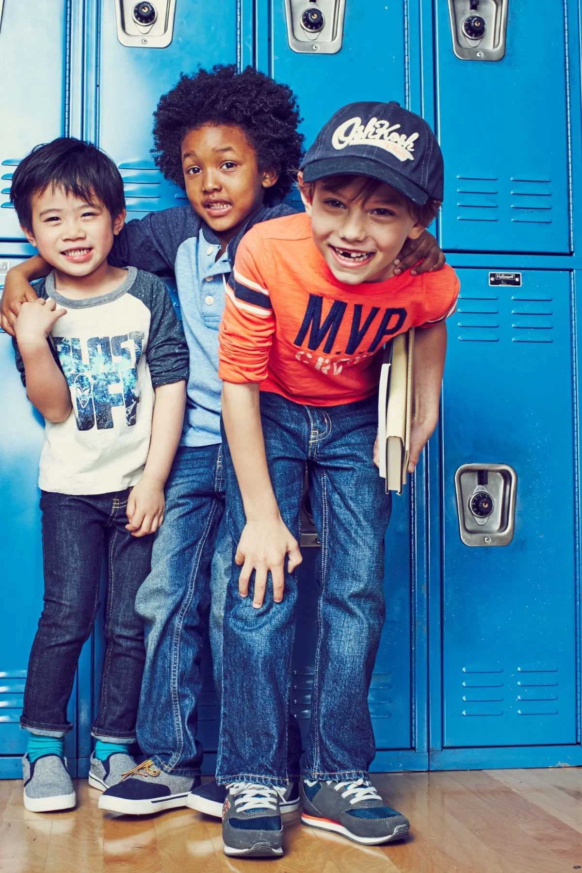 Three boys standing in front of blue school lockers, smiling and posing for the camera.