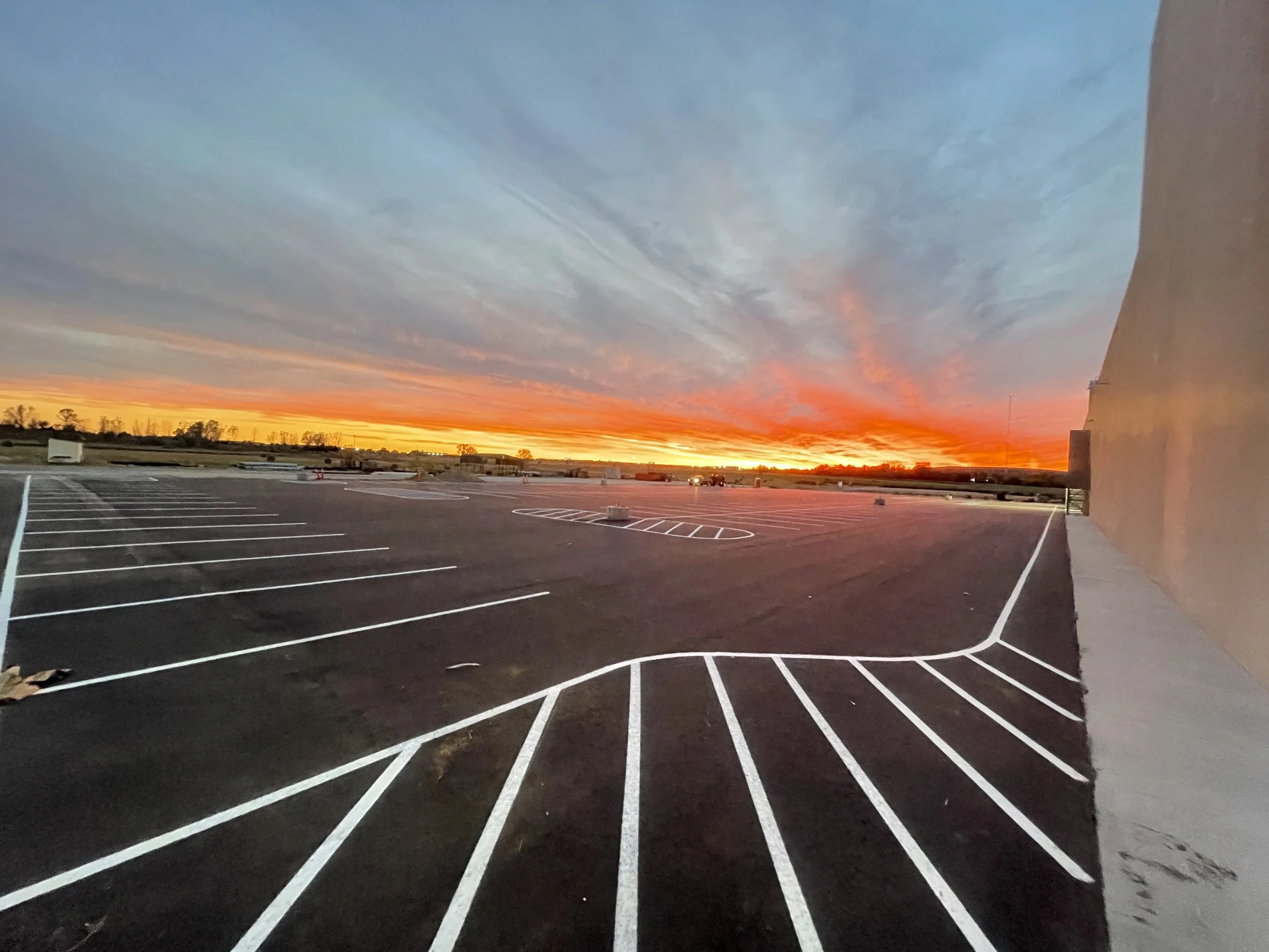 Empty parking lot at sunset with colorful sky and clouds.