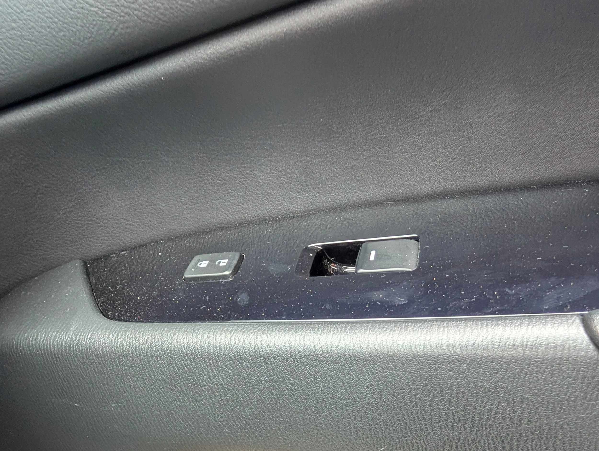 Close-up of a car's interior showing window control buttons on the door panel.