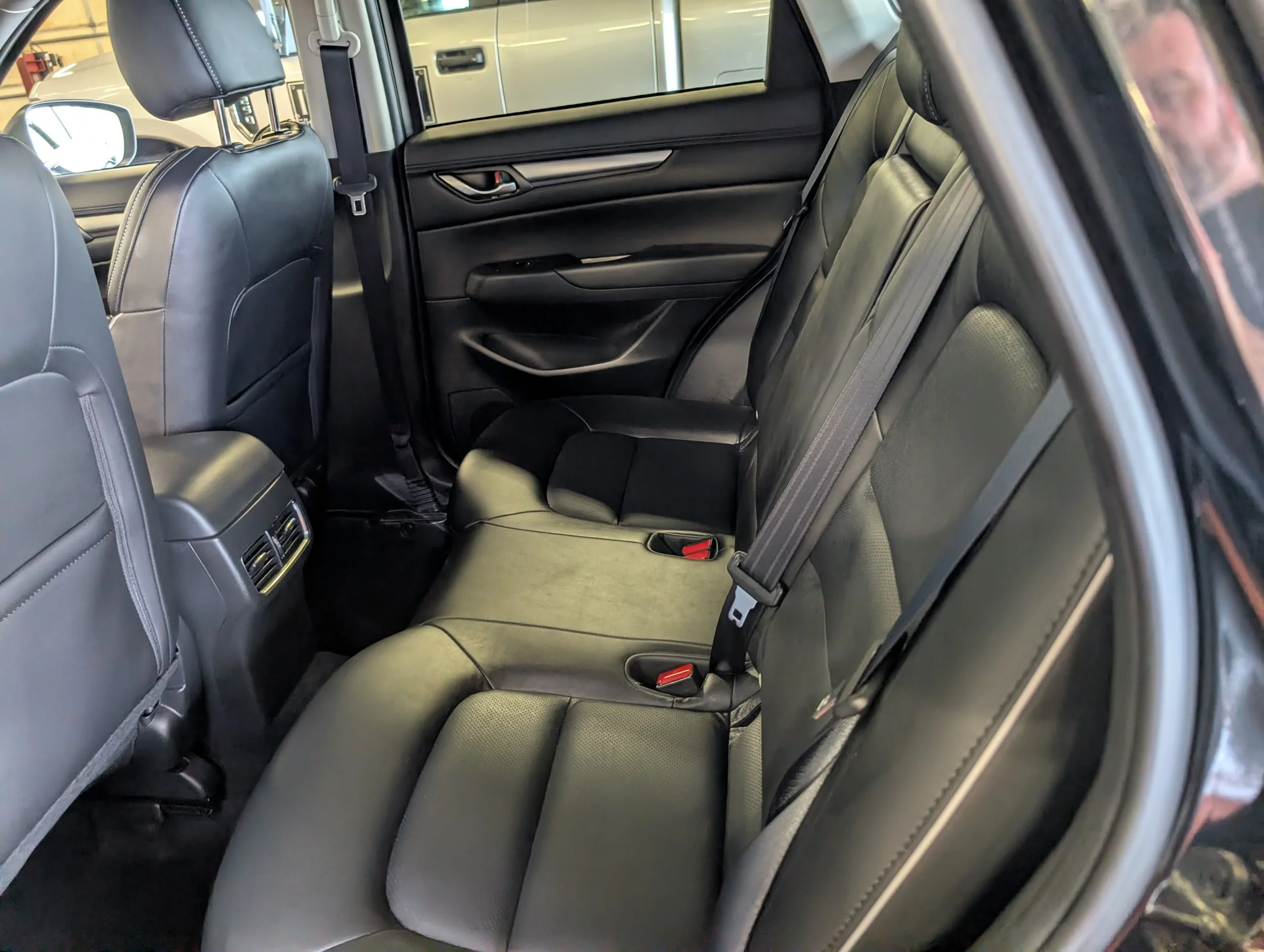 Interior of a car showing the back seats and front headrests, black leather seats, and rear air vents.