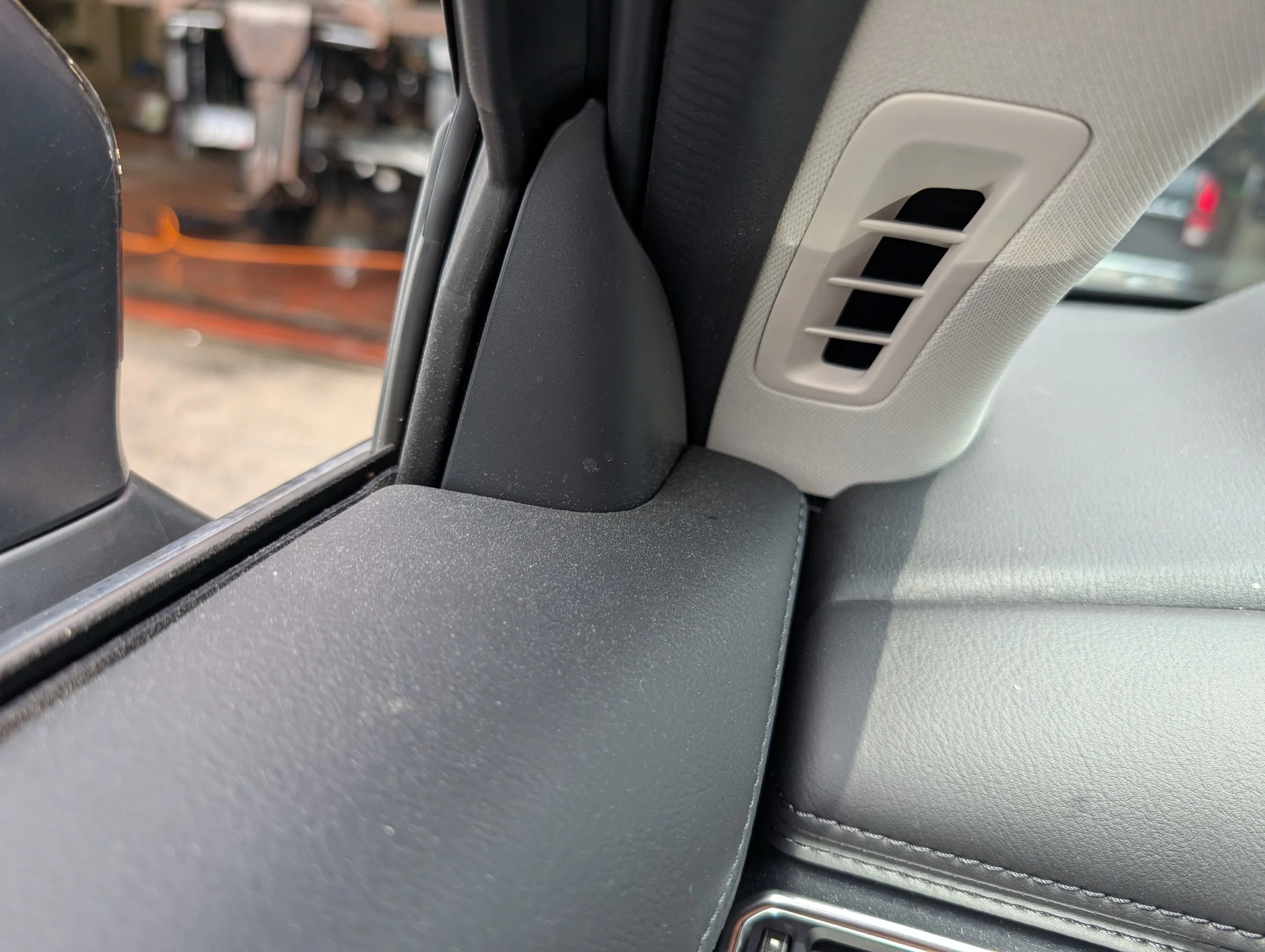 A close-up view of a car's interior overhead vent near the sun visor and rearview mirror.