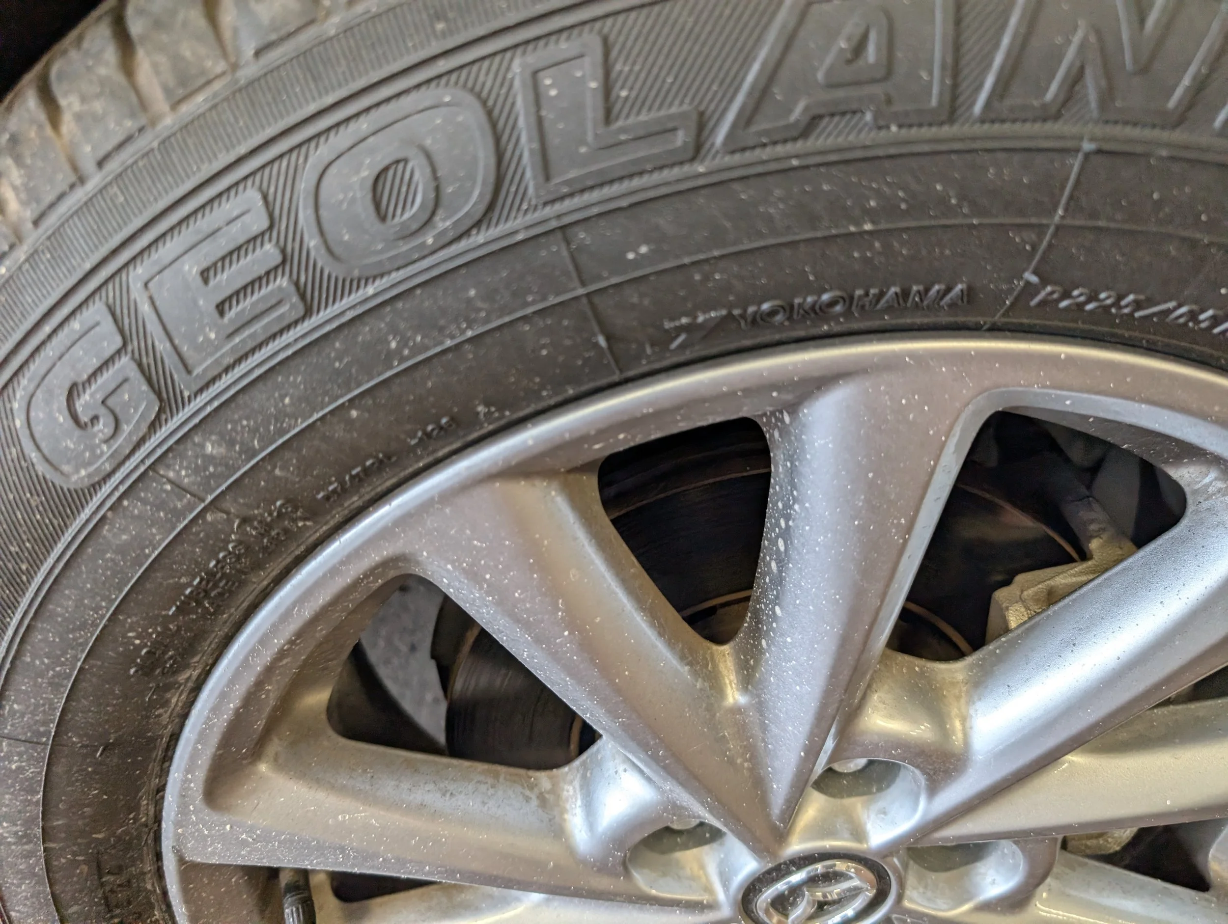 Close-up of a car tire with visible brand name 'YOKOHAMA' and part of the alloy wheel, with dirt and grime on the surface.