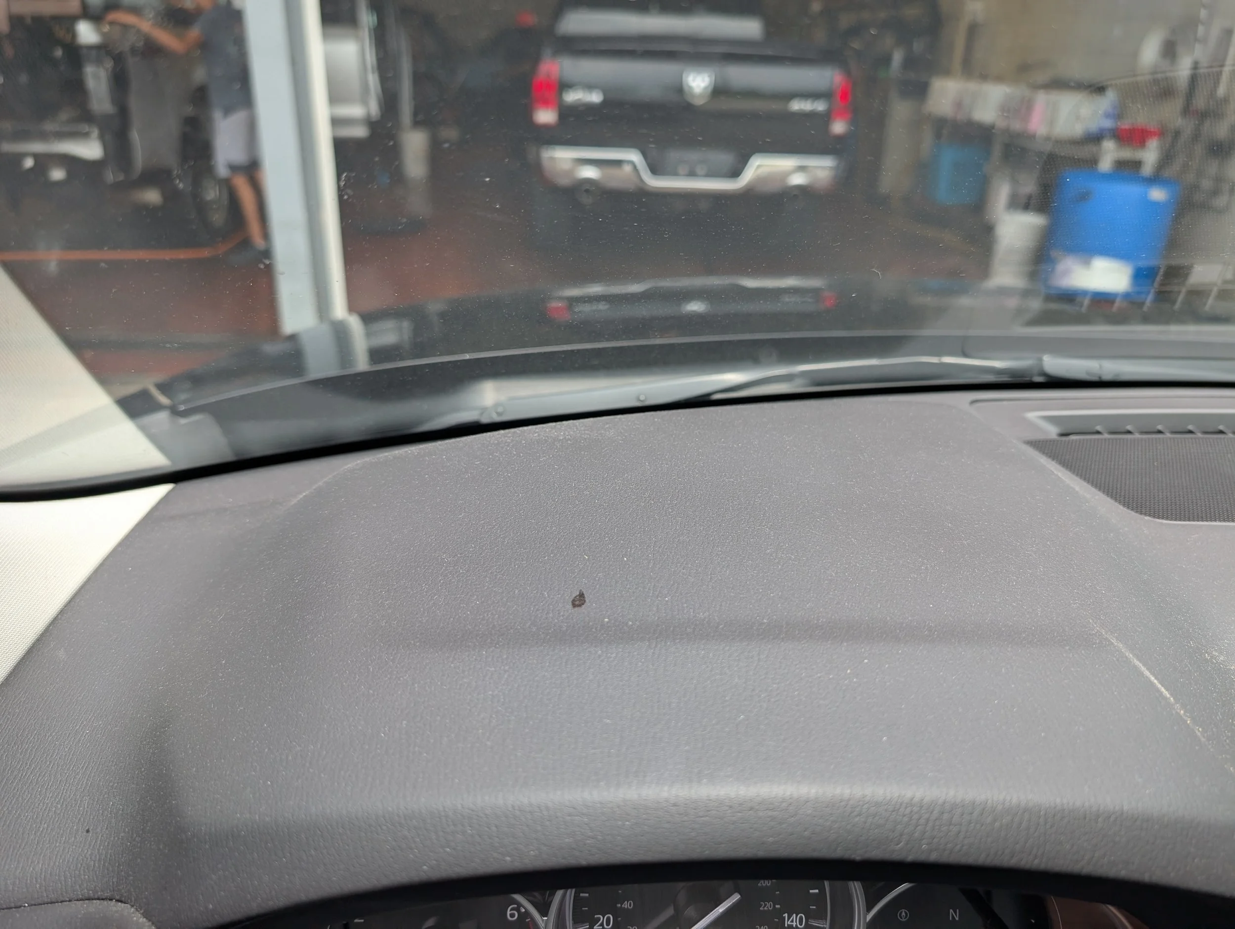 View from inside a vehicle showing a garage with tools and other items, with a black pickup truck parked ahead.