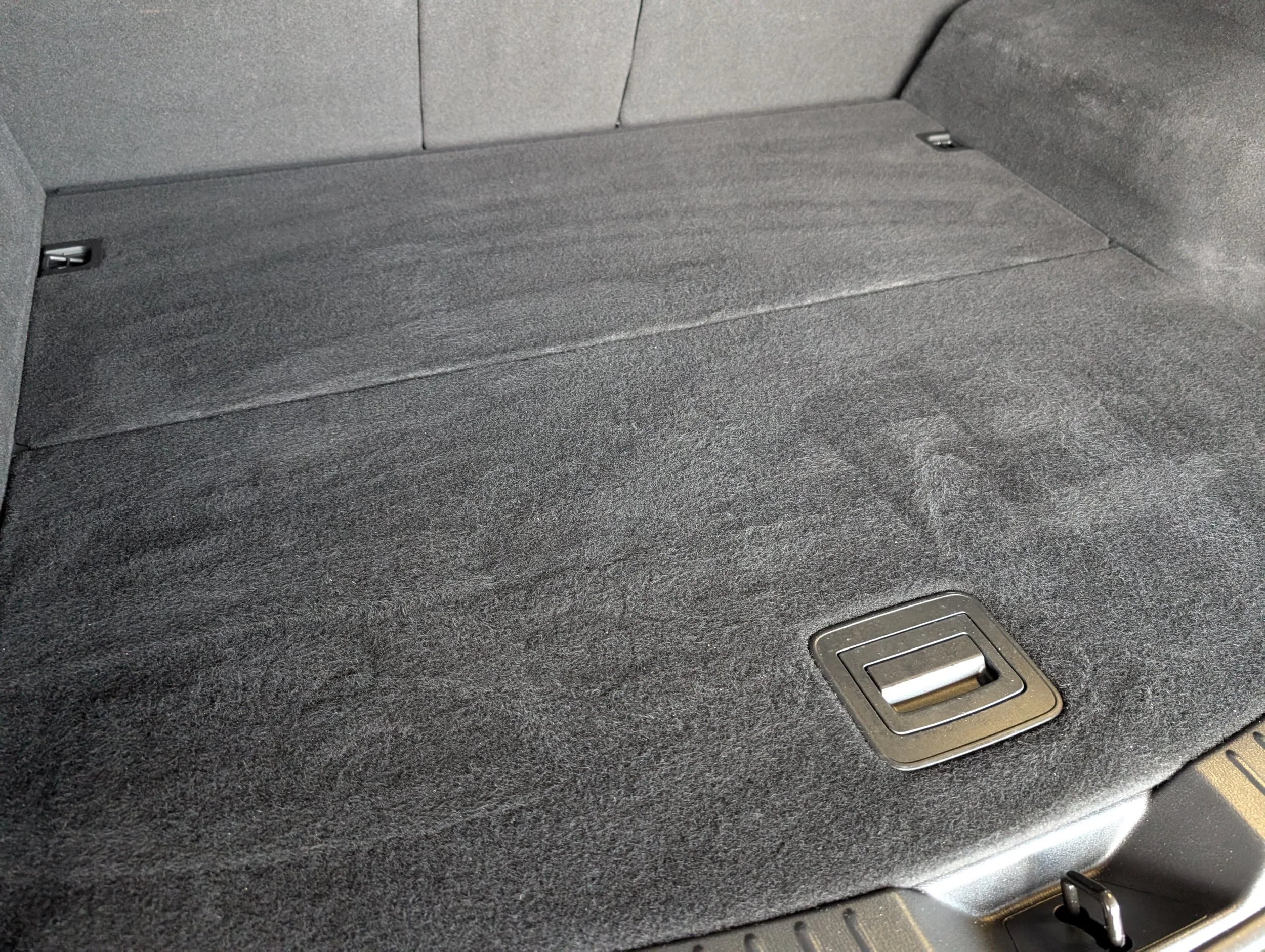 Close-up image of a car's carpeted floor with a floor vent.