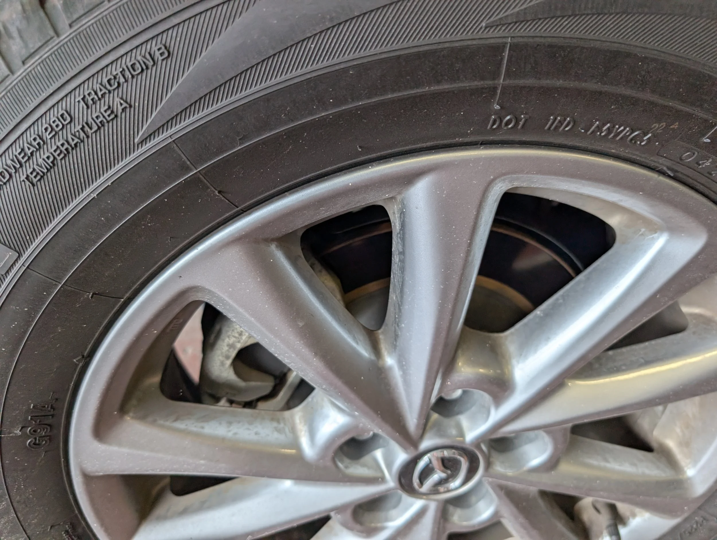 Close-up of a car tire mounted on a silver alloy wheel, showing brand markings and tire details.