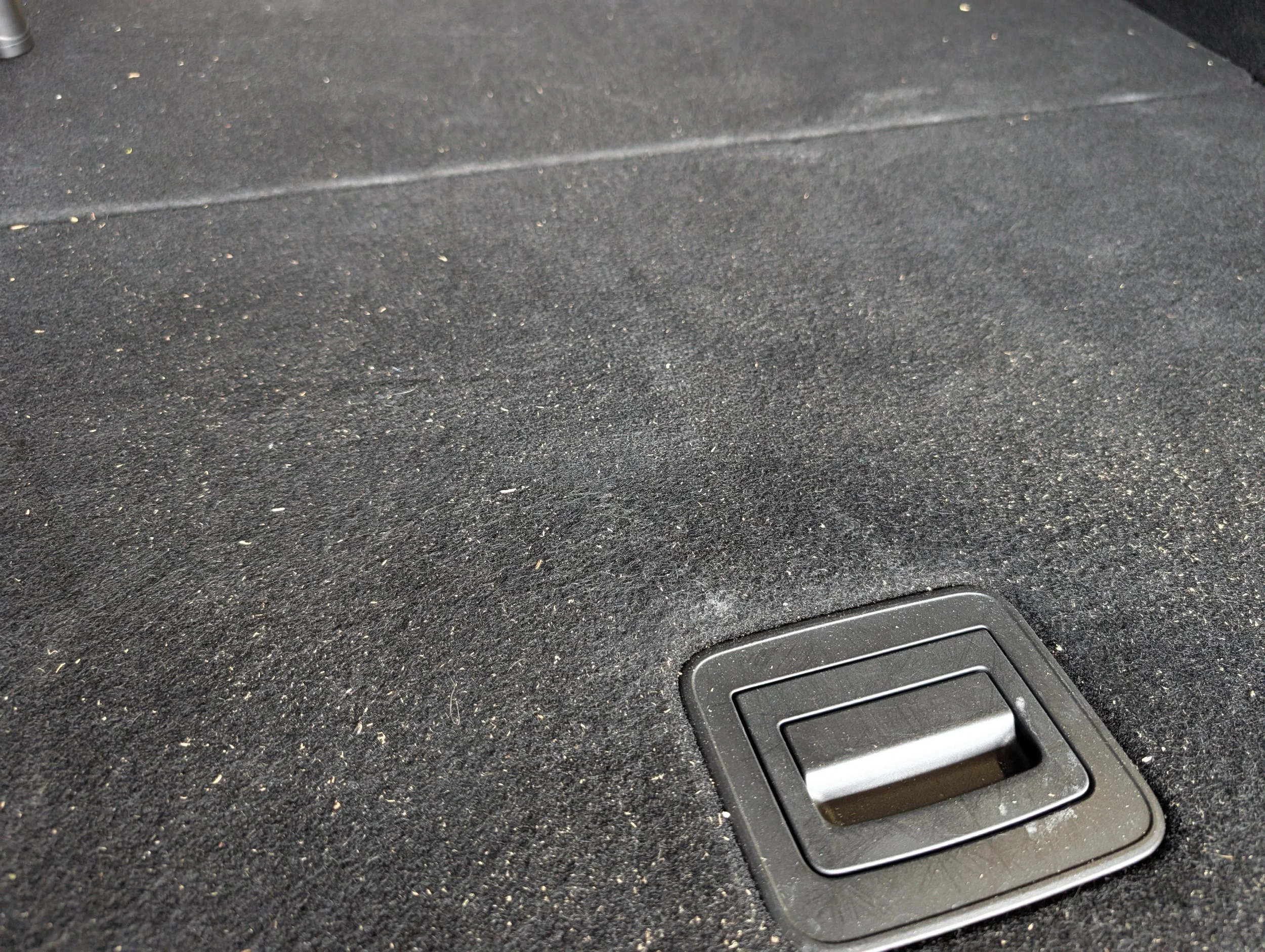 Close-up of a black textured surface with a rectangular air vent at the bottom right corner.
