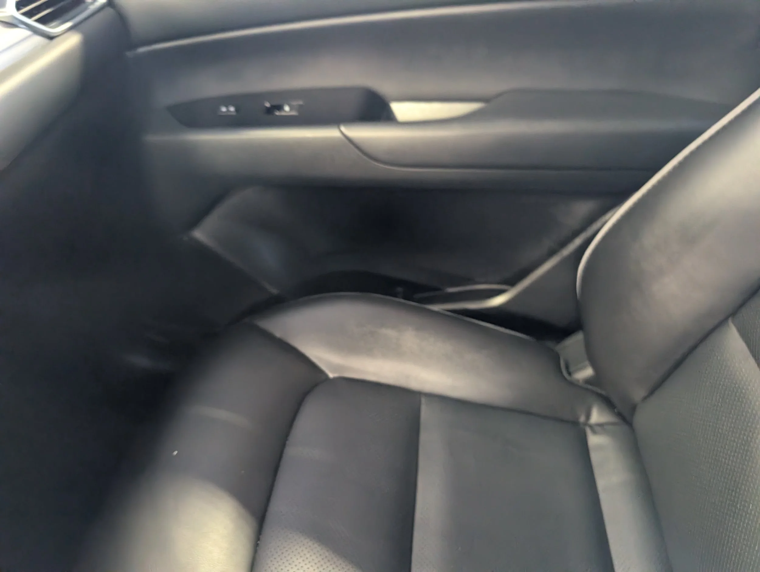 The interior of a car's backseat area showing the door panel, part of the seat, and the window.