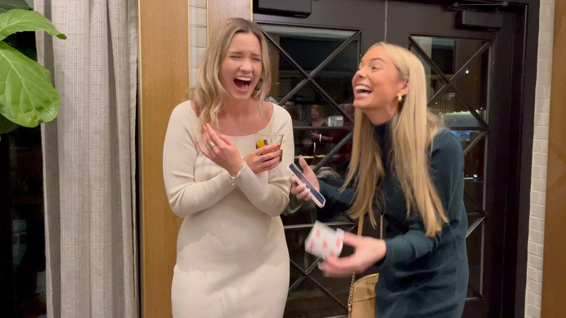 Two women laughing and sharing a moment at a social gathering