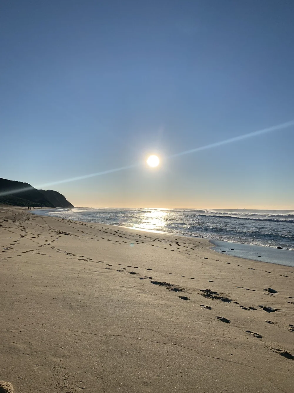 Sun over the beach at the headland