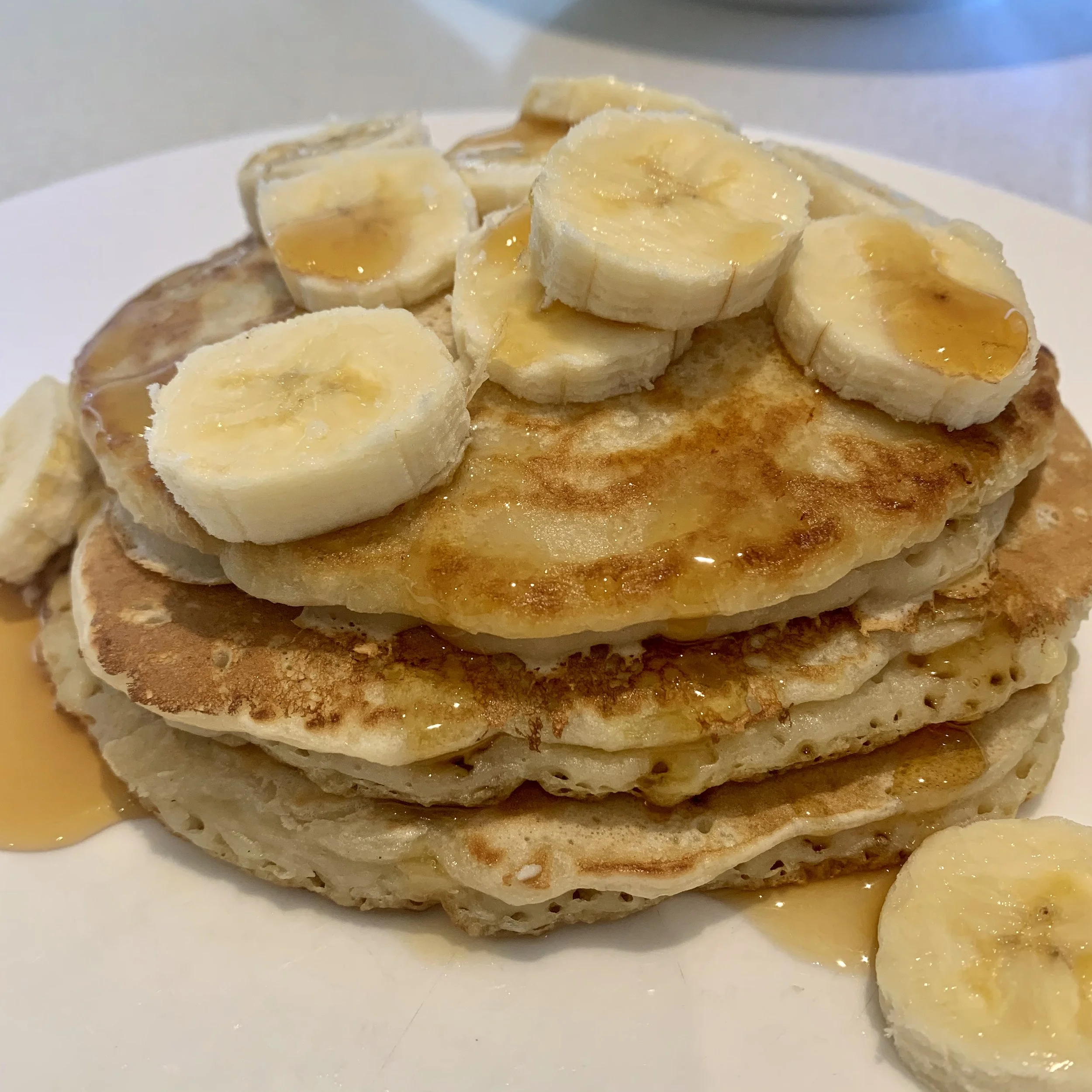 A stack of banana pancakes with maple syrup