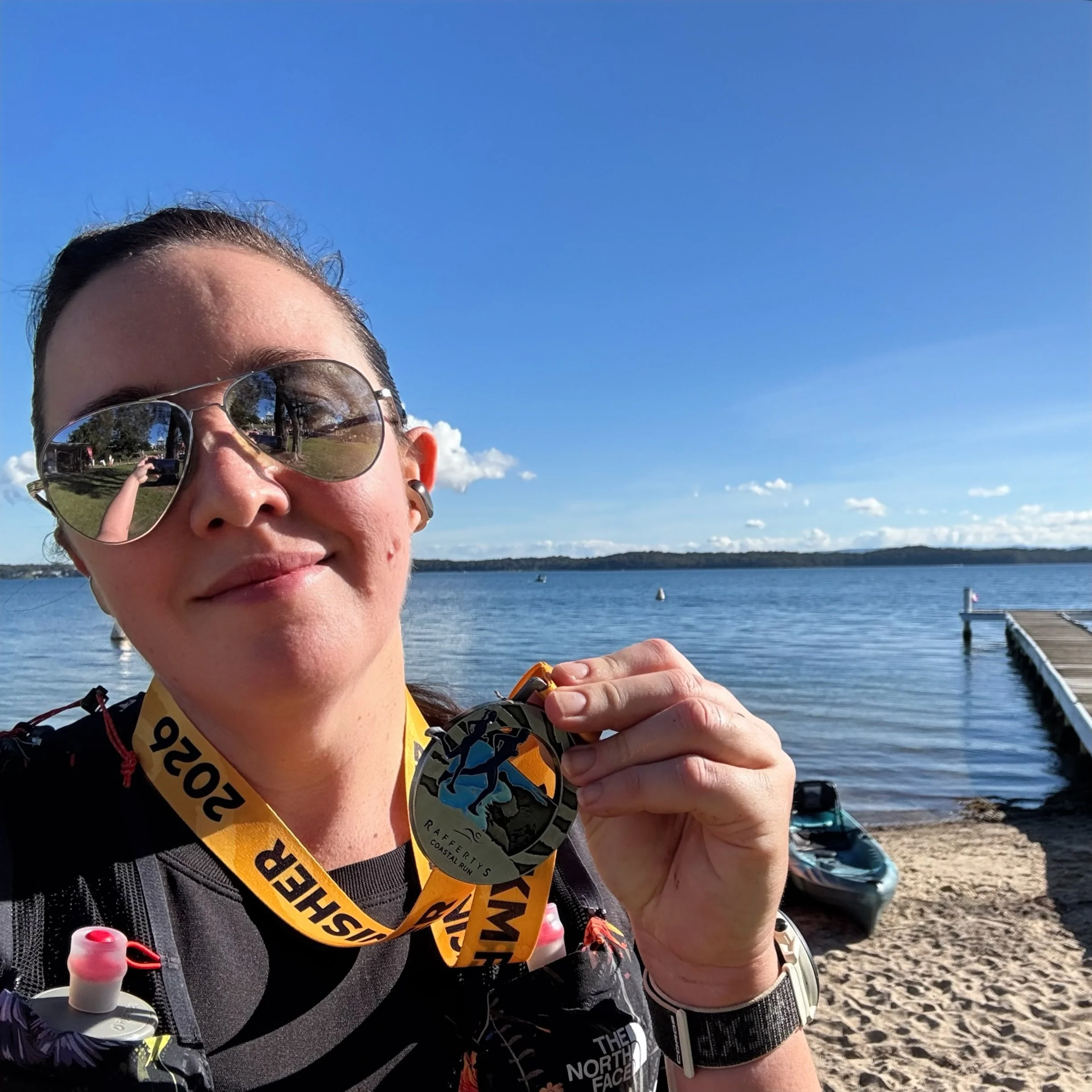 Holding the finisher medal by the lake after the race