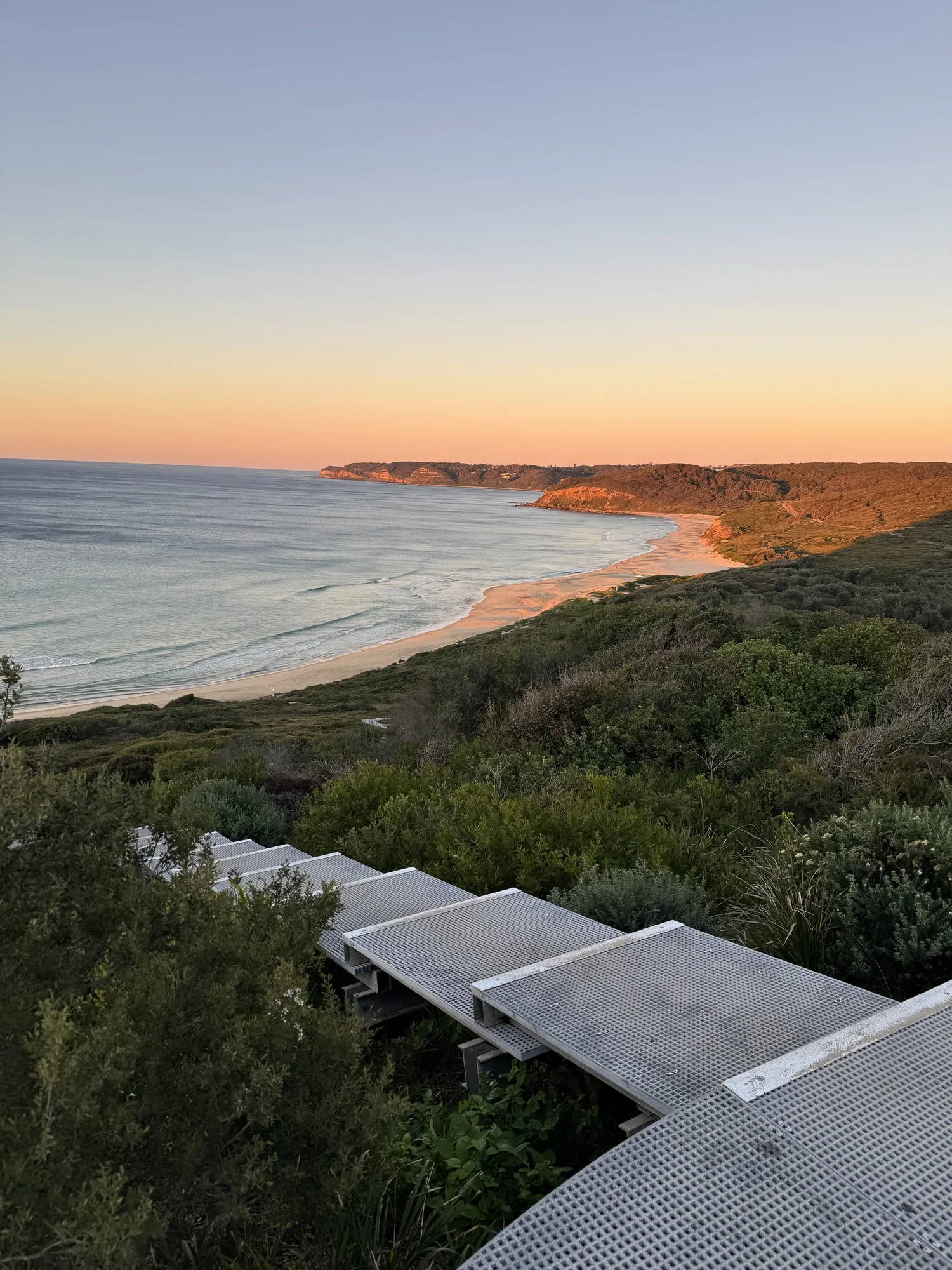 A metal boardwalk descending toward the beach at Glenrock at sunrise