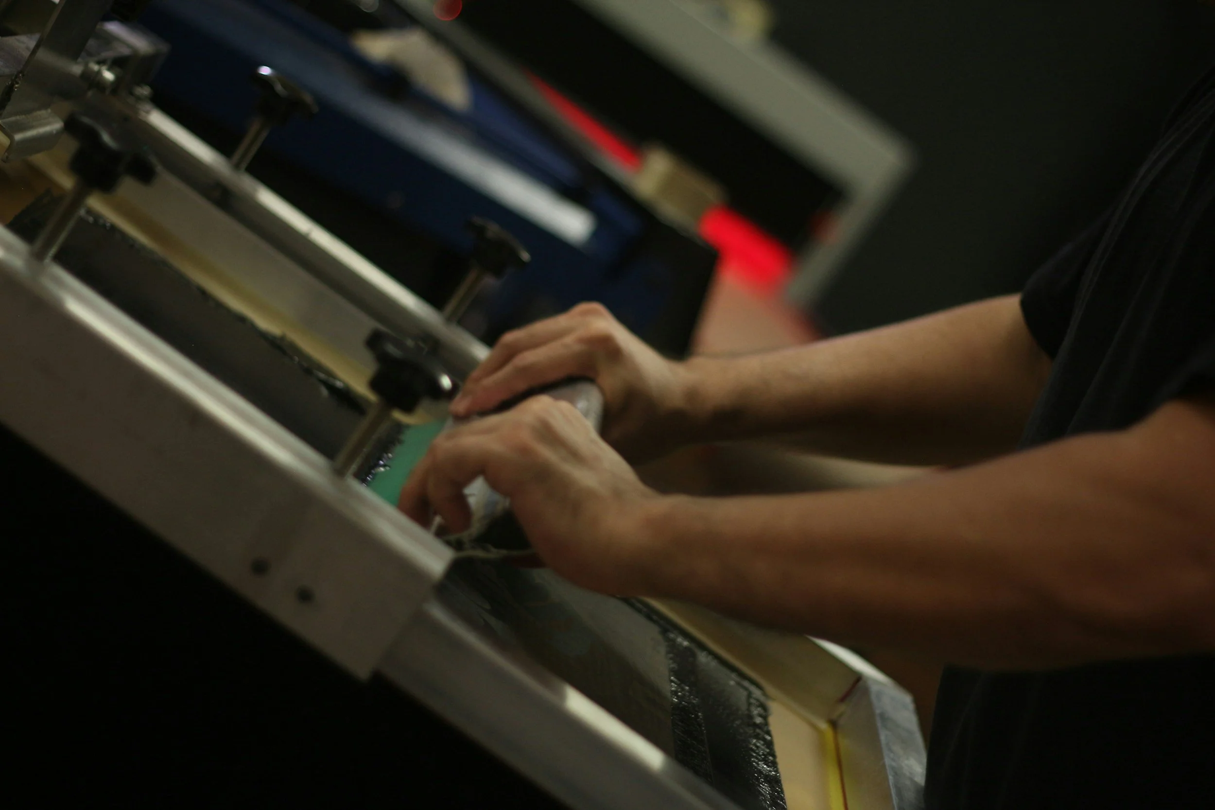 A person working with machinery or equipment, holding a tool or part, in a workshop or manufacturing environment.