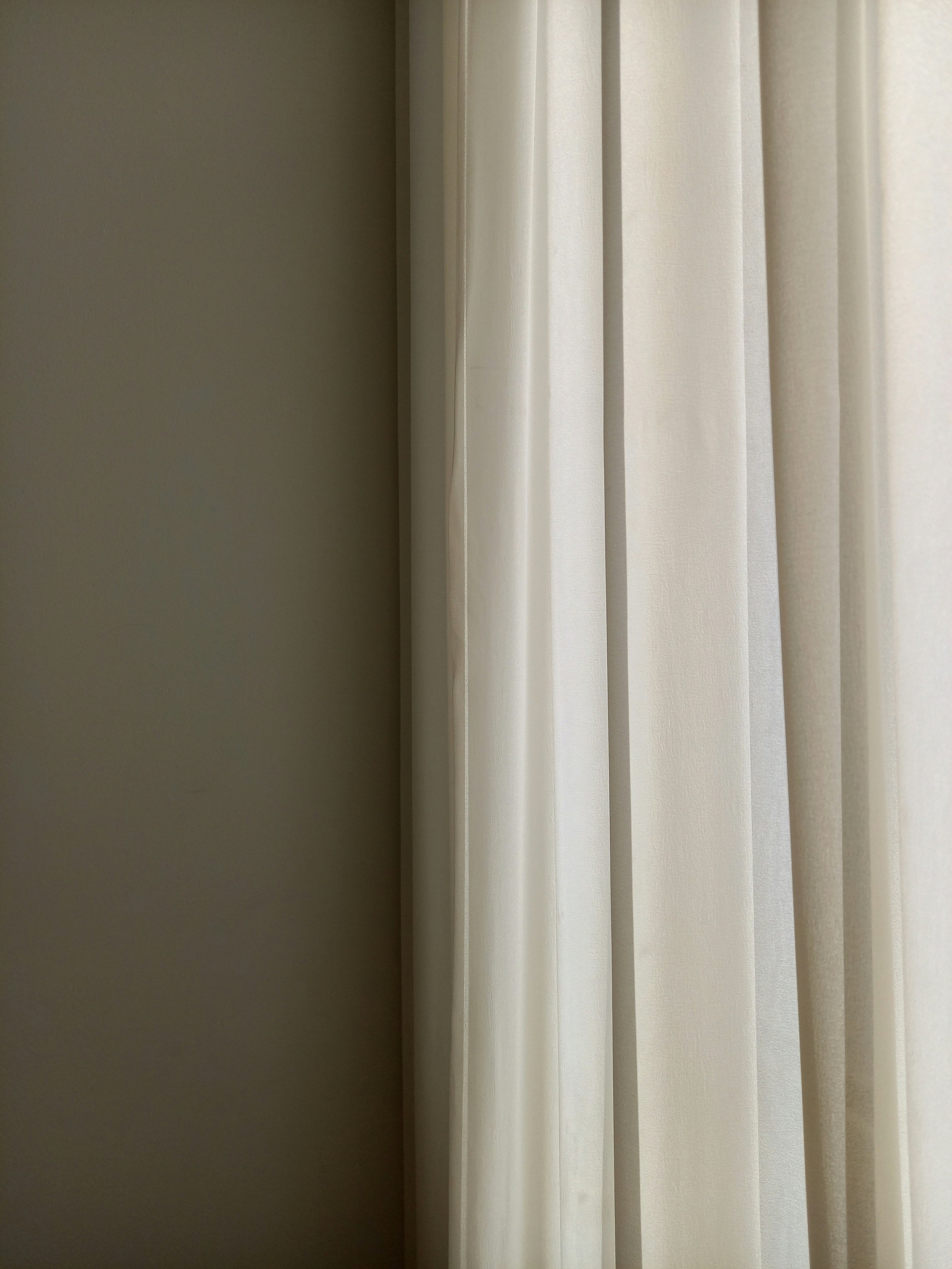 A beige wall and cream-colored vertical blinds covering a window.