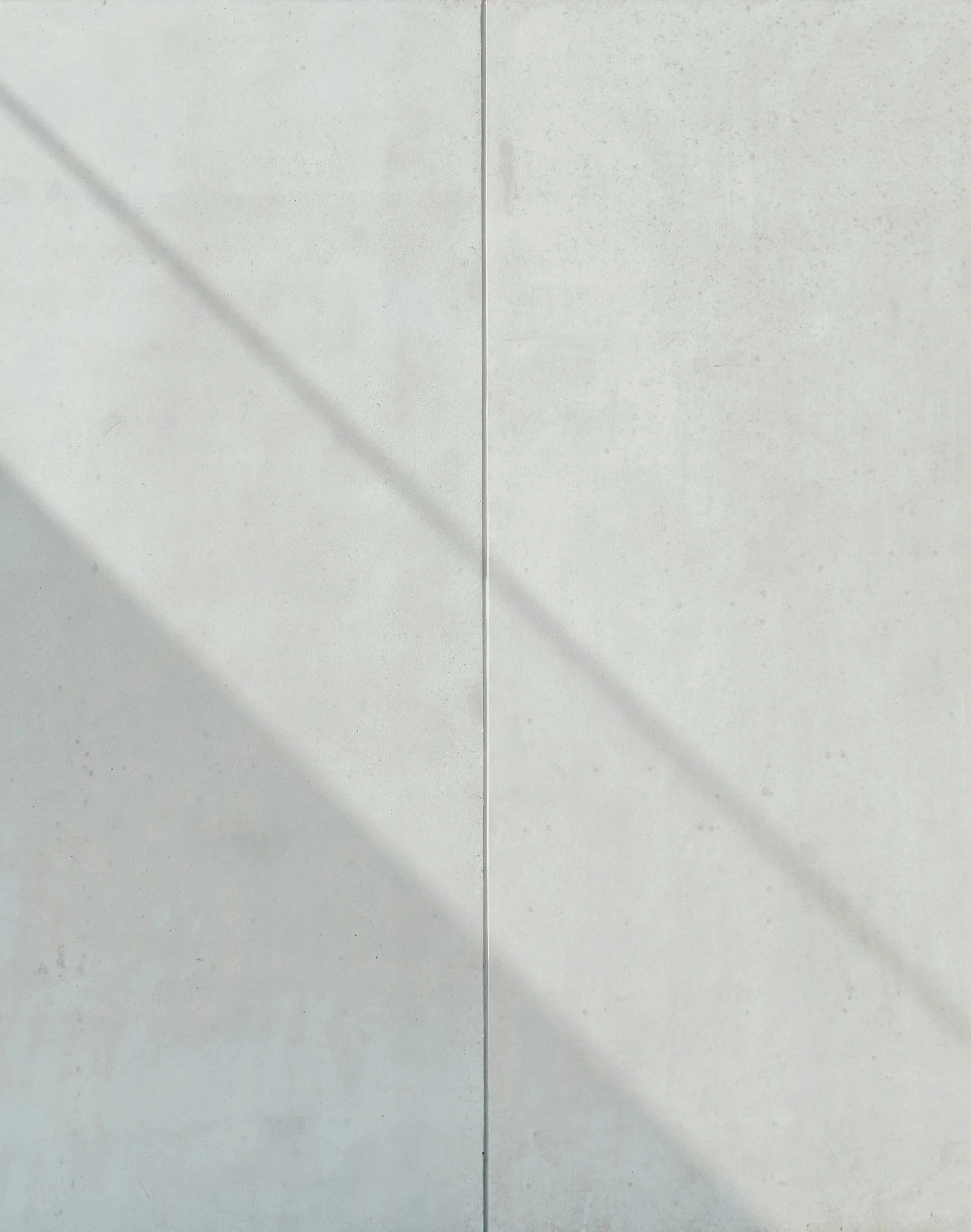 Close-up of a white tiled wall with grout lines and a faint diagonal shadow.