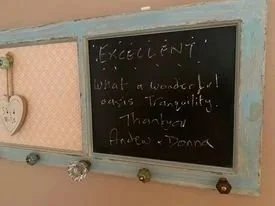 A blackboard with a handwritten message that reads: 'EXCELLENT! what a wonderful oasis tranquility. Thanuva, Andrew, Donna.'