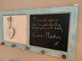 A chalkboard with a handwritten thank you message, decorated with a heart-shaped ornament and colorful beads along the bottom edge.