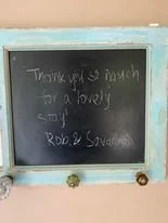 A chalkboard with a wooden frame, displaying a handwritten message in white chalk.
