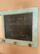 A chalkboard with a decorative, blue and white frame, thanking guests for visiting or staying.