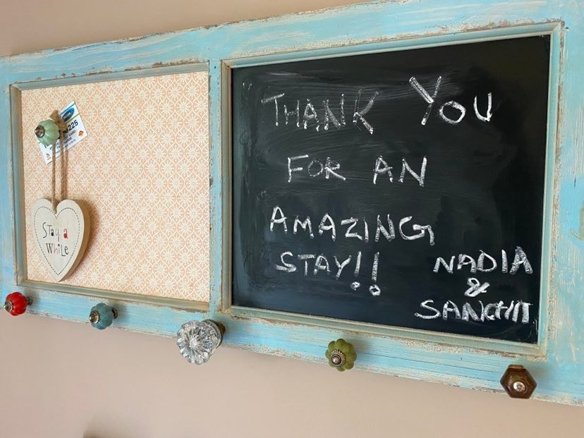 A chalkboard and a corkboard on a wall, with a handmade heart-shaped decoration hanging from the corkboard and colorful knobs attached at the bottom of the boards. The chalkboard has a message written in chalk that says, 'Thank you for an amazing sta