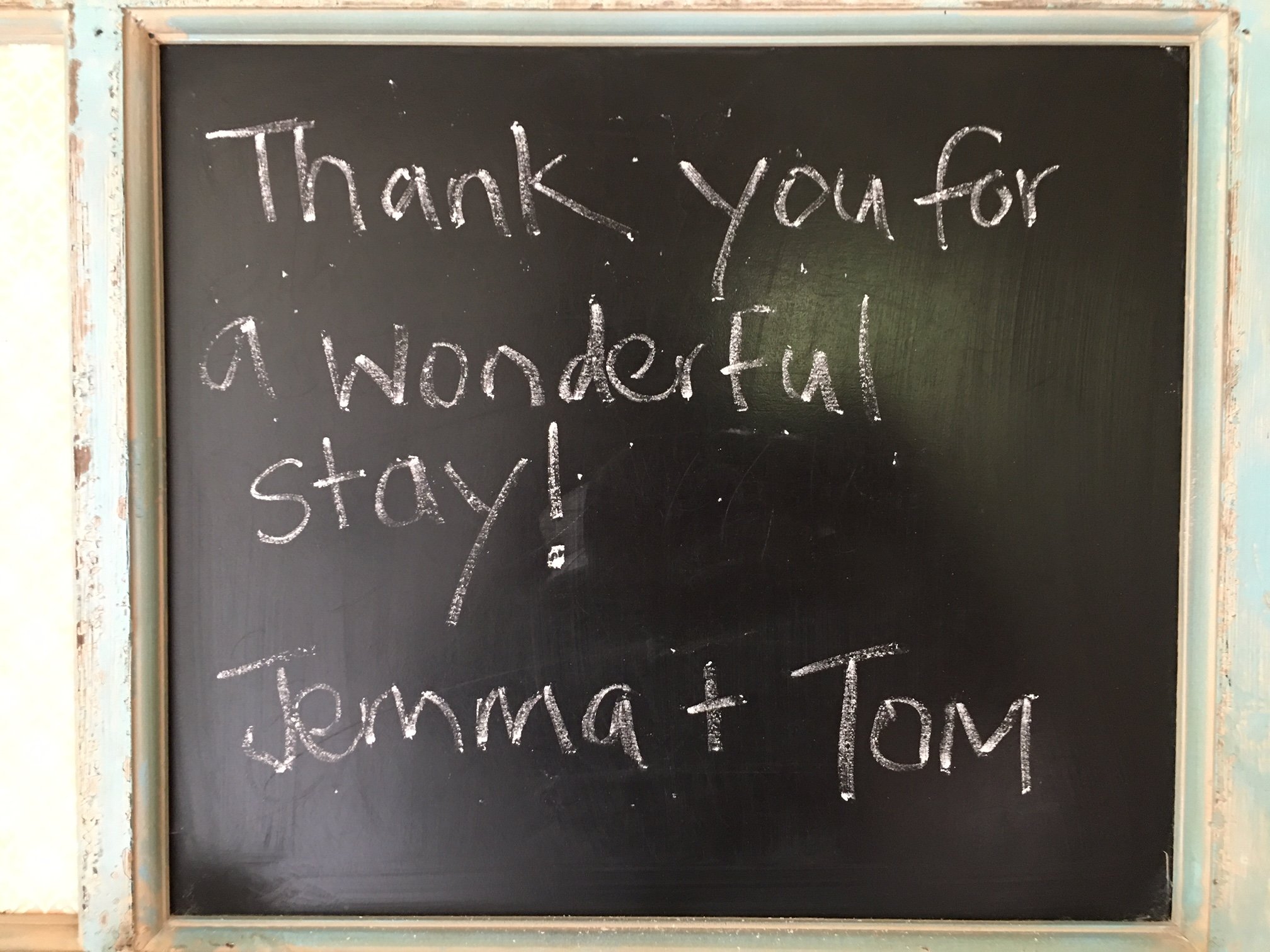 A black chalkboard with a copper-colored frame, displaying handwritten words in white chalk that say "Thank you for a wonderful stay!"