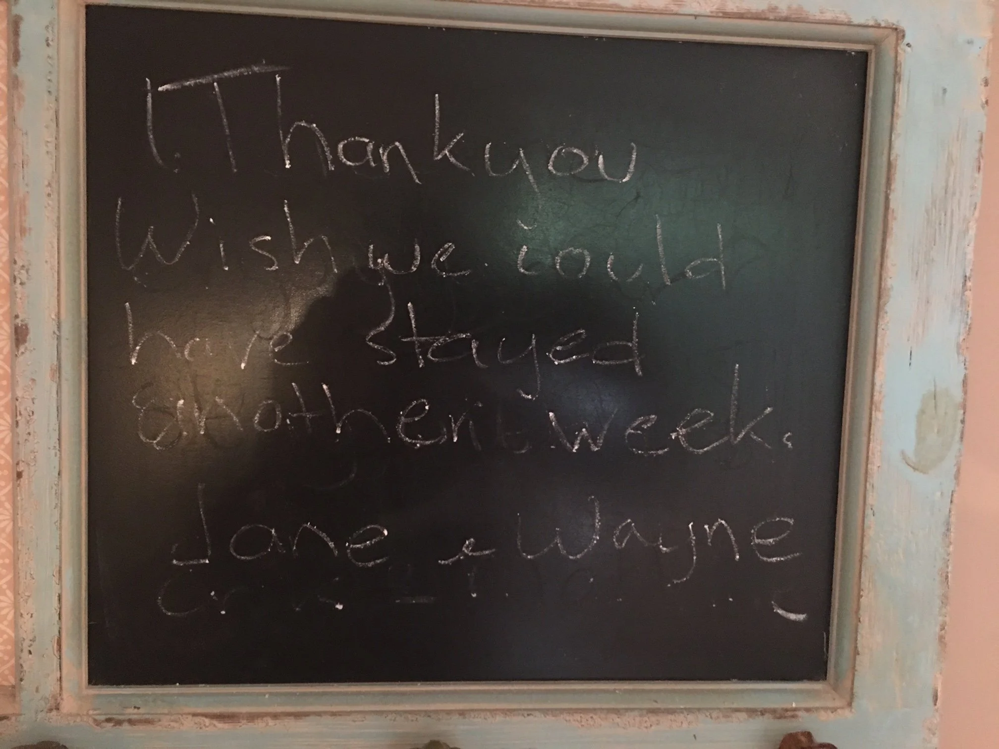 A chalkboard with the handwritten message 'Thank you, wish we could have stayed longer.'