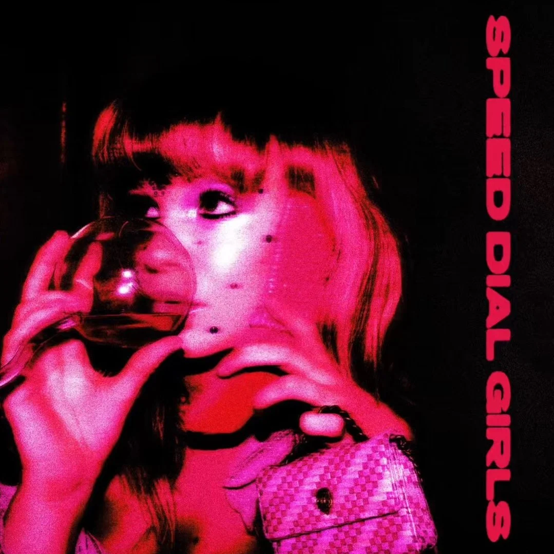 A woman with dark hair and bangs holds a reflective sphere near her eye, with the reflection showing her face. The image has a pink and black color scheme, and the text 'SPELDIAL GIRLS' is written vertically on the right side.