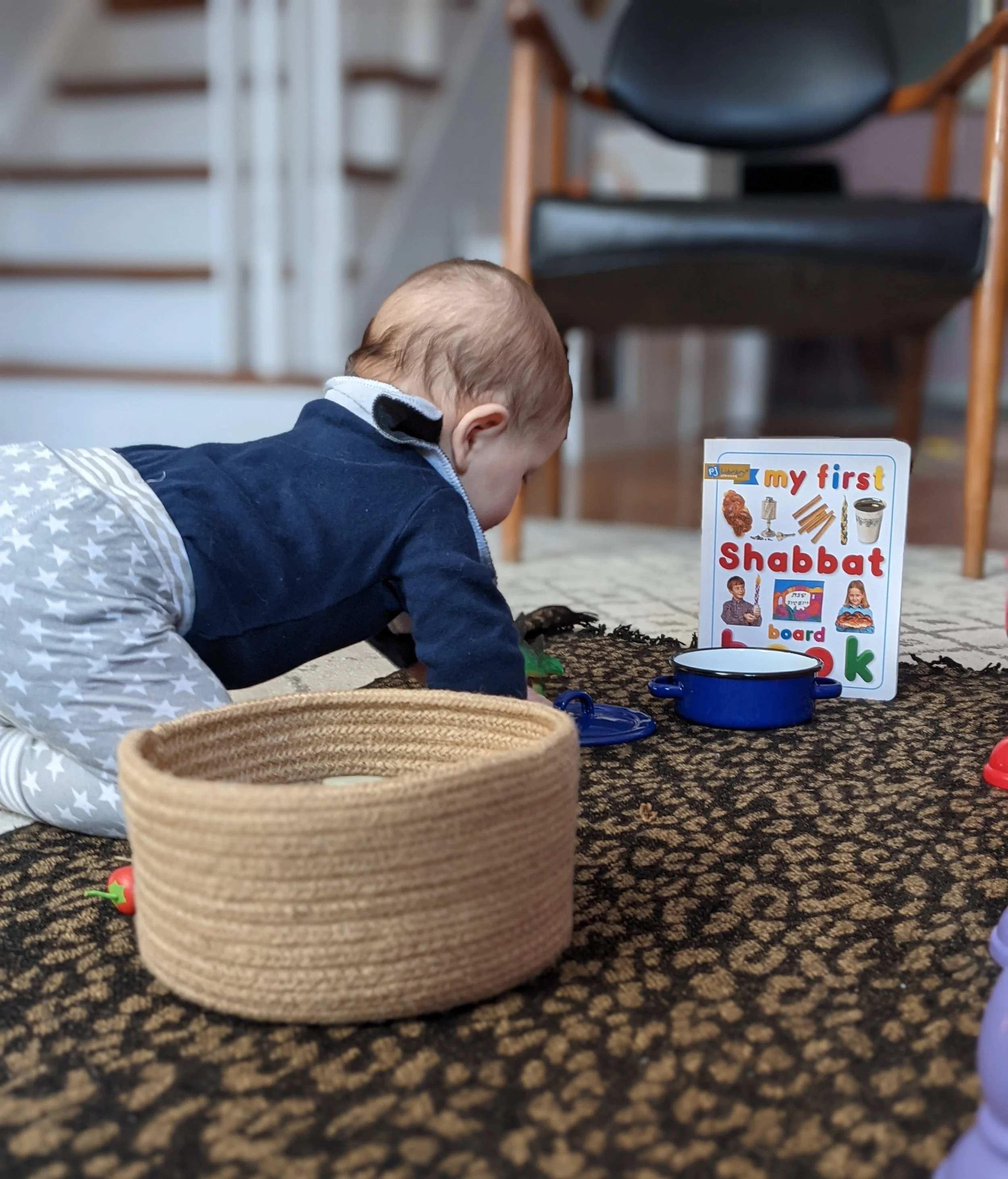 Young child explores Shabbat materials, books, and sensory toys