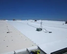 A snow-covered rooftop with equipment and cables, under a clear blue sky.