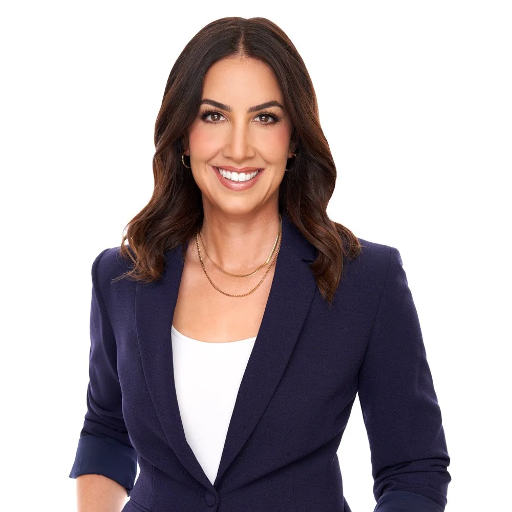 Portrait of a smiling woman with shoulder-length brown hair, wearing a navy blazer and white top, against a plain white background.