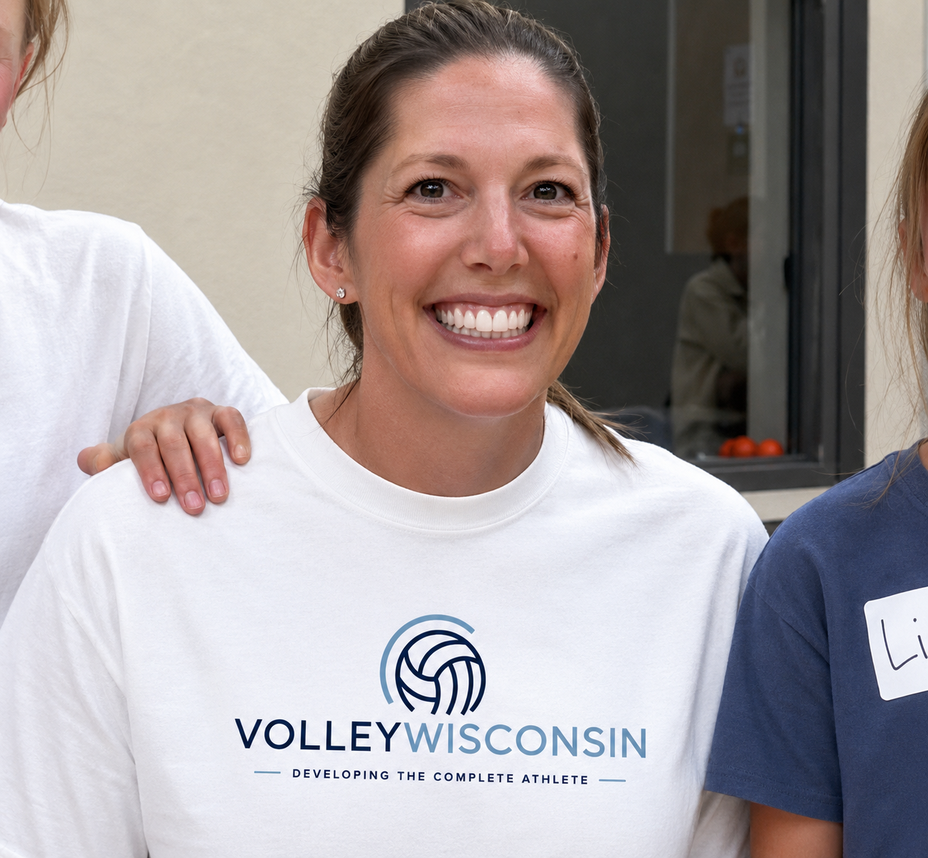 A woman smiling wearing a volleyball t-shirt with 'Volleyball Wisconsin' and a volleyball logo.