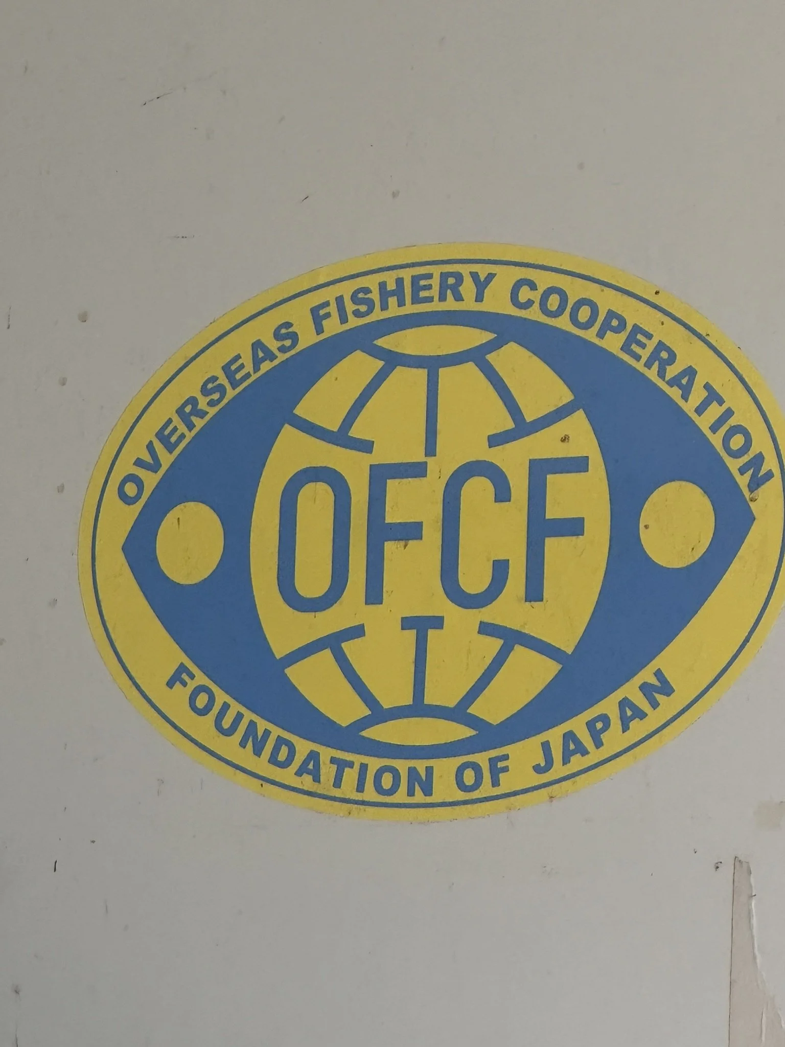 Logo of the OverSeas Fishery Cooperative, Foundation of Japan, featuring a circular design with a globe and the organization's name in blue and yellow colors.