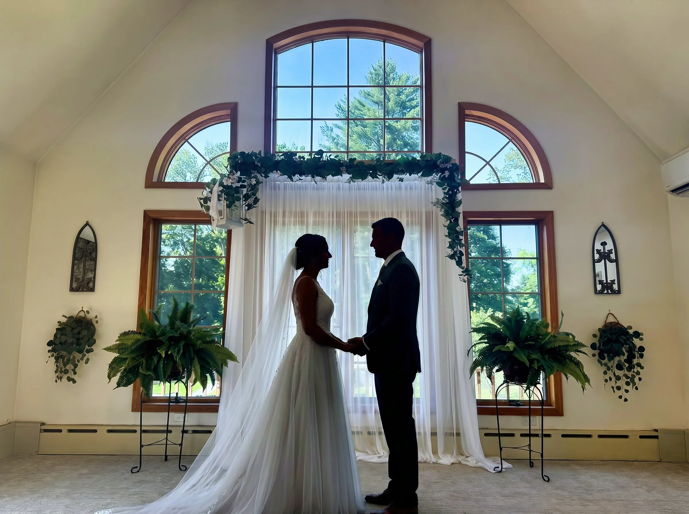 Bride and Groom in front of beautiful wedding arch in beautiful gathering room at Storybook Cottage.