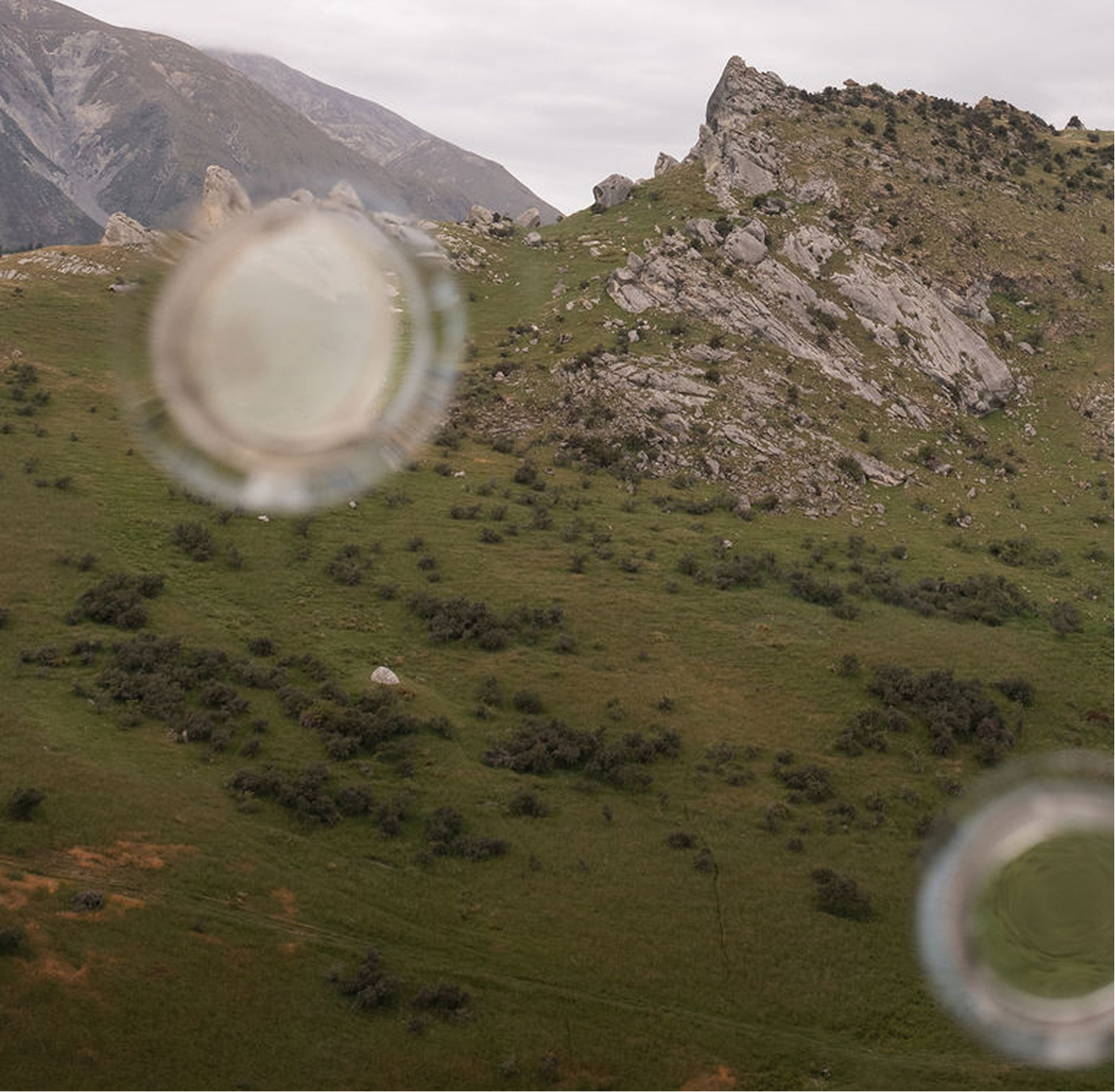 View of mountainous landscape seen through multiple out-of-focus glass cups.