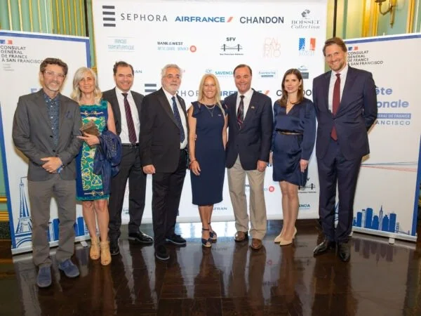 Group of seven professionals, four men and three women, standing together in front of a backdrop with logos of Sephora, Air France, Chandon, and others at a corporate event in San Francisco.