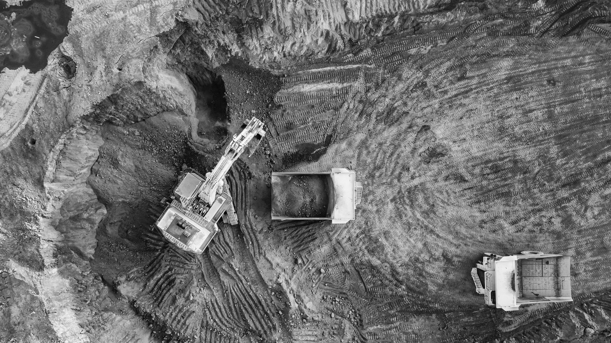 An aerial view of a mining site with an excavator and Haul Truck operating to load ore onto the truck. The teams operating these pieces of equipment will be trained and competent to do so.