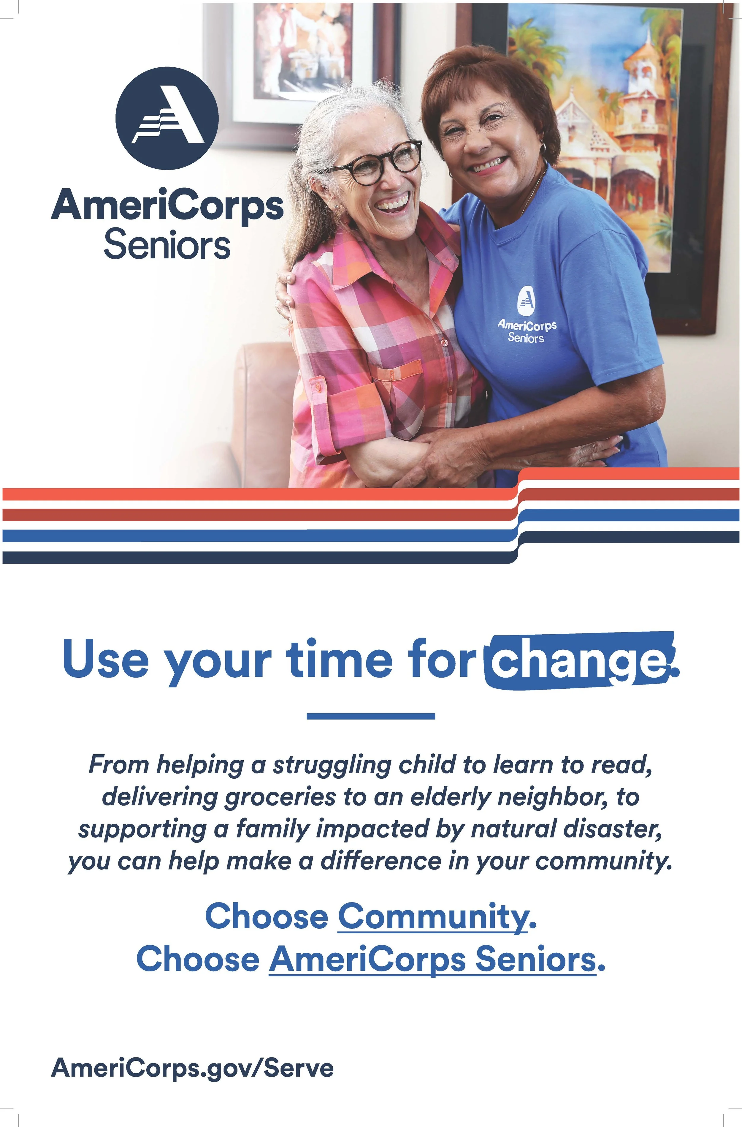 Two smiling elderly women hugging each other indoors, one wearing glasses and a pink plaid shirt, the other in a blue shirt with a logo, with colorful artwork hanging on the wall behind them.