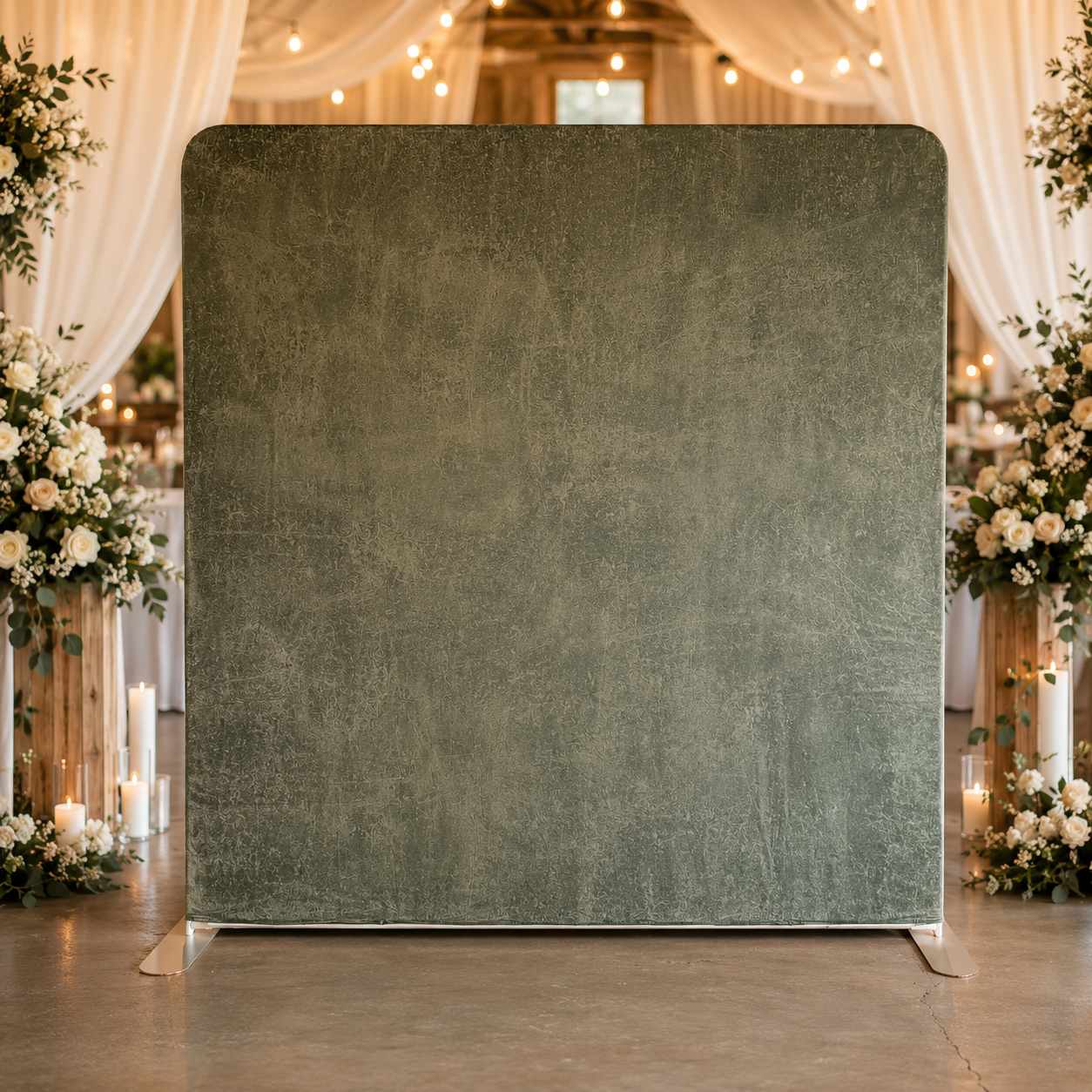 A large green velvet room divider in a decorated wedding venue with floral arrangements and candles in the background.
