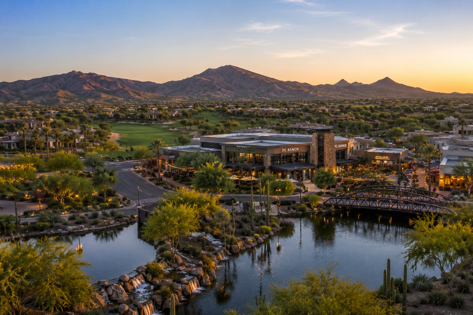 Aerial view of DC Ranch in North Scottsdale featuring Market Street, golf course views, desert landscaping, and the McDowell Mountains at sunset.
