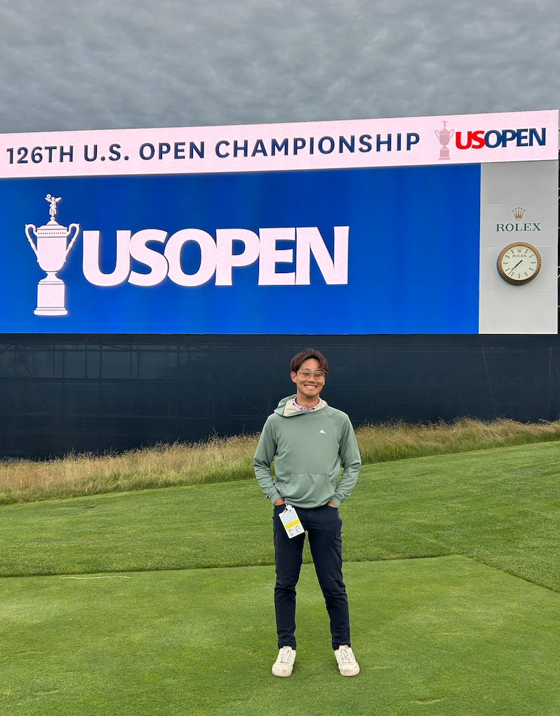 Robert Lee standing in front of a screen at the 2026 US Open during Monday practice rounds with PGA tour player and LIV tour player Peter Uihlein